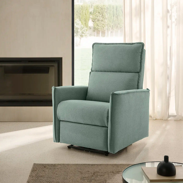 Sillón relax tapizado en verde agua, abierto en un salón junto a la chimenea