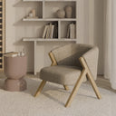 Butaca SINTRA, en beige, en un salón con estantería blanca y alfombra clara