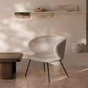 Butaca ANCONA, en beige, en un salón de microcemento junto a un banco de madera