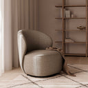Butaca HAVANA, en taupe, junto a una estantería de madera y cortina de lino