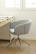 Silla ADD con reposabrazos y pie giratorio cromado, en gris claro, junto a un escritorio – Teulat