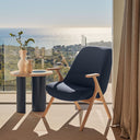 Butaca DINS con patas de haya natural, en azul oscuro, en una terraza con vistas – Teulat