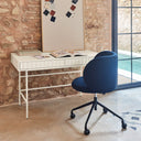Silla de escritorio MOGI con ruedas en azul marino, en un escritorio junto a una ventana – Teulat