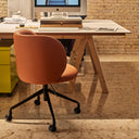 Silla de escritorio MOGI con ruedas en polipiel terracota, en una mesa de trabajo – Teulat