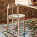 Silla NARA en natural claro, junto a una mesa de comedor – Teulat
