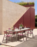 Mesa Tevere 210 extensible en tortora con sillones Cassia en borgoña, en una terraza – Nardi