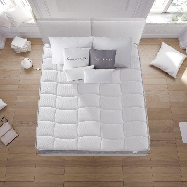 Esta búsqueda no produjo información específica. Reescribiendo la descripción en menos de 90 caracteres: Una cama ordenada con edredón blanco y varias almohadas en un dormitorio minimalista.