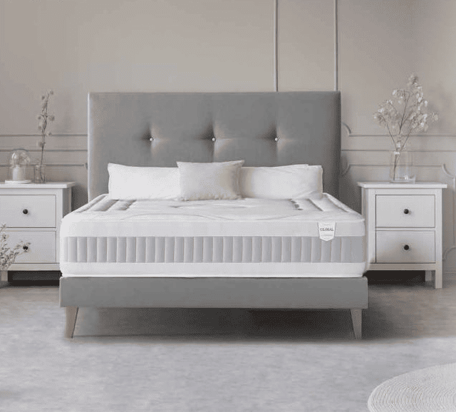 Cama grande con dos mesitas de noche y decoración minimalista en tonos neutros.