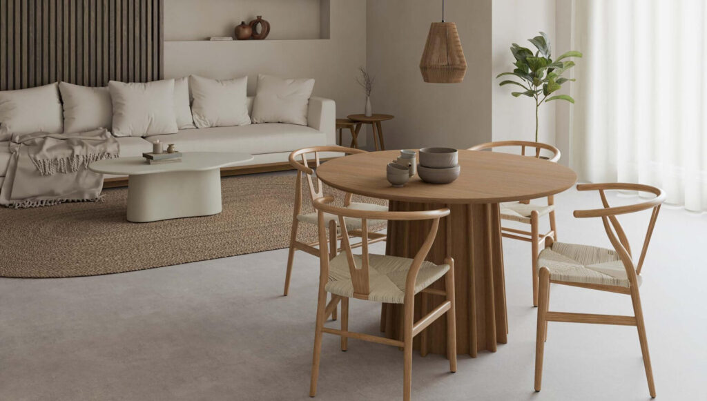 Juego de comedor con mesa de madera y sillas tejidas. Sofá blanco y decoración neutra.